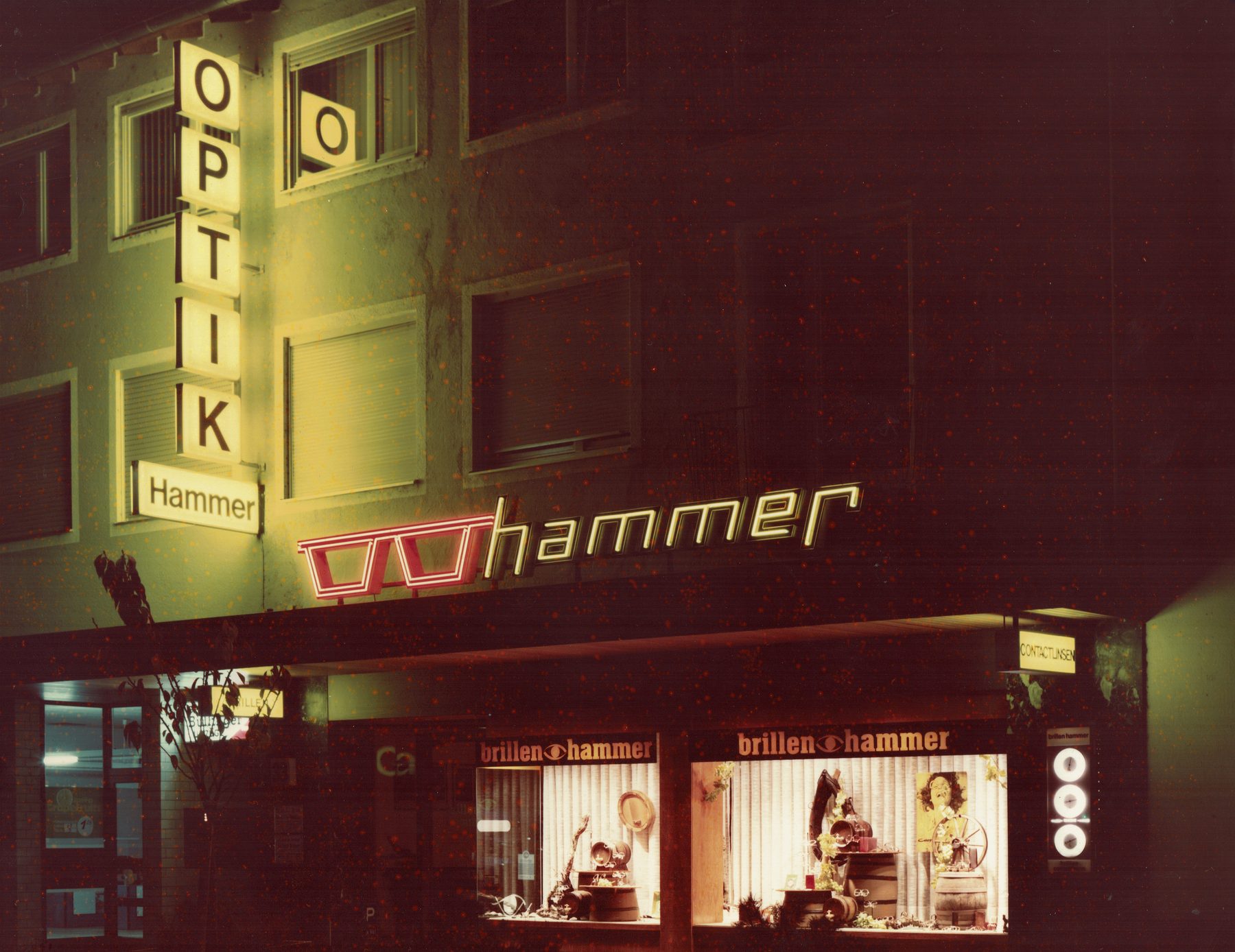 brillenhammer Landau in den Anfangsjahren: Fassade mit Leuchtreklame bei Nacht