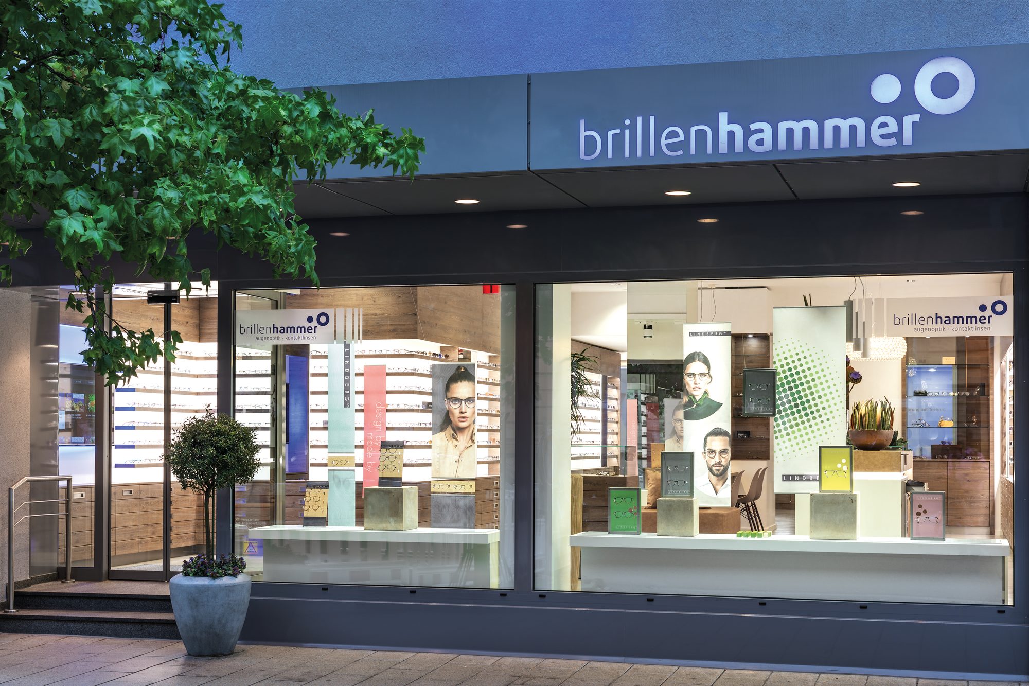 brillenhammer Landau: beleuchtete Fassade mit Schaufenstern am Abend